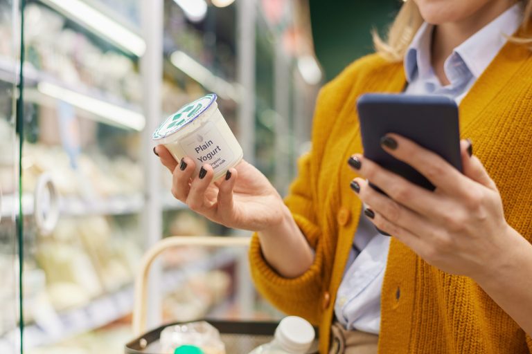 Woman using phone shopping in supermarket